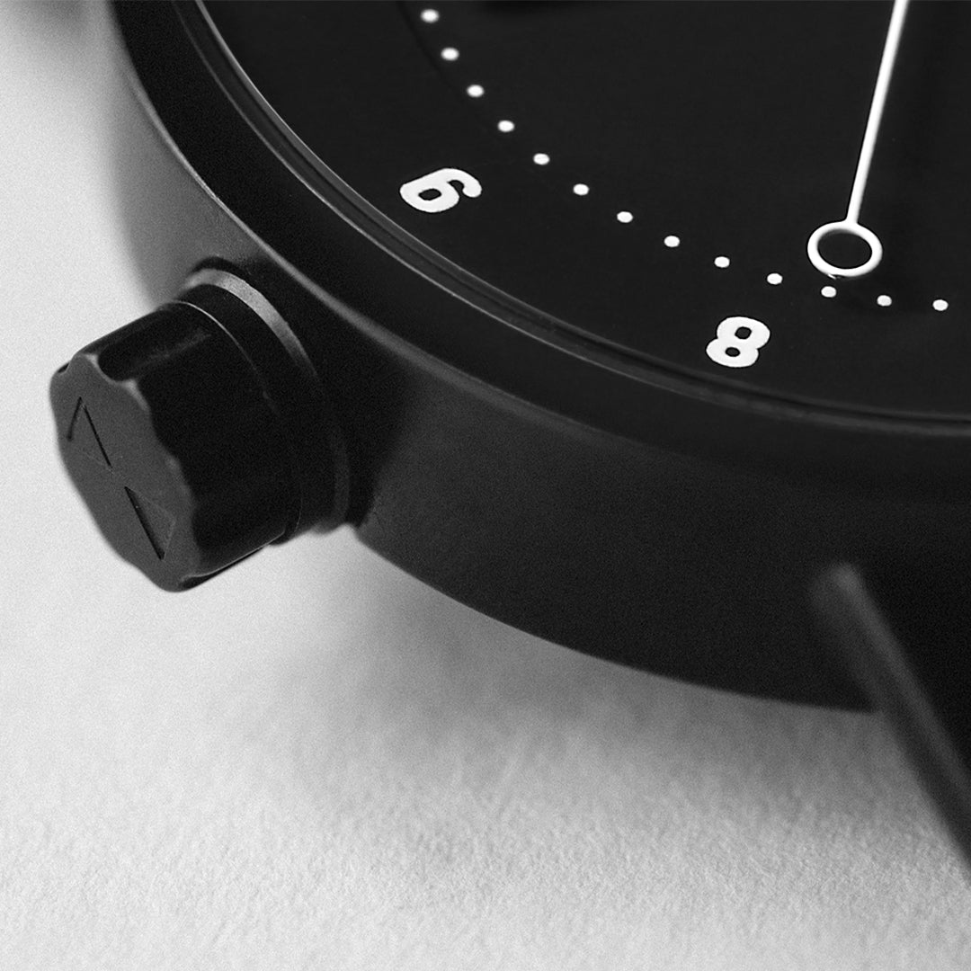 Close-up of TID No.1 black dial watch showing round-tip second hand and 9 o’clock crown