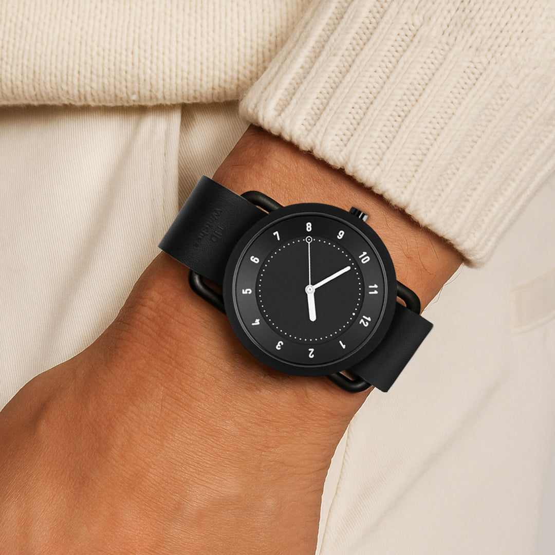 TID No.1 black dial minimalist men’s watch with black leather strap worn with cream knit sweater