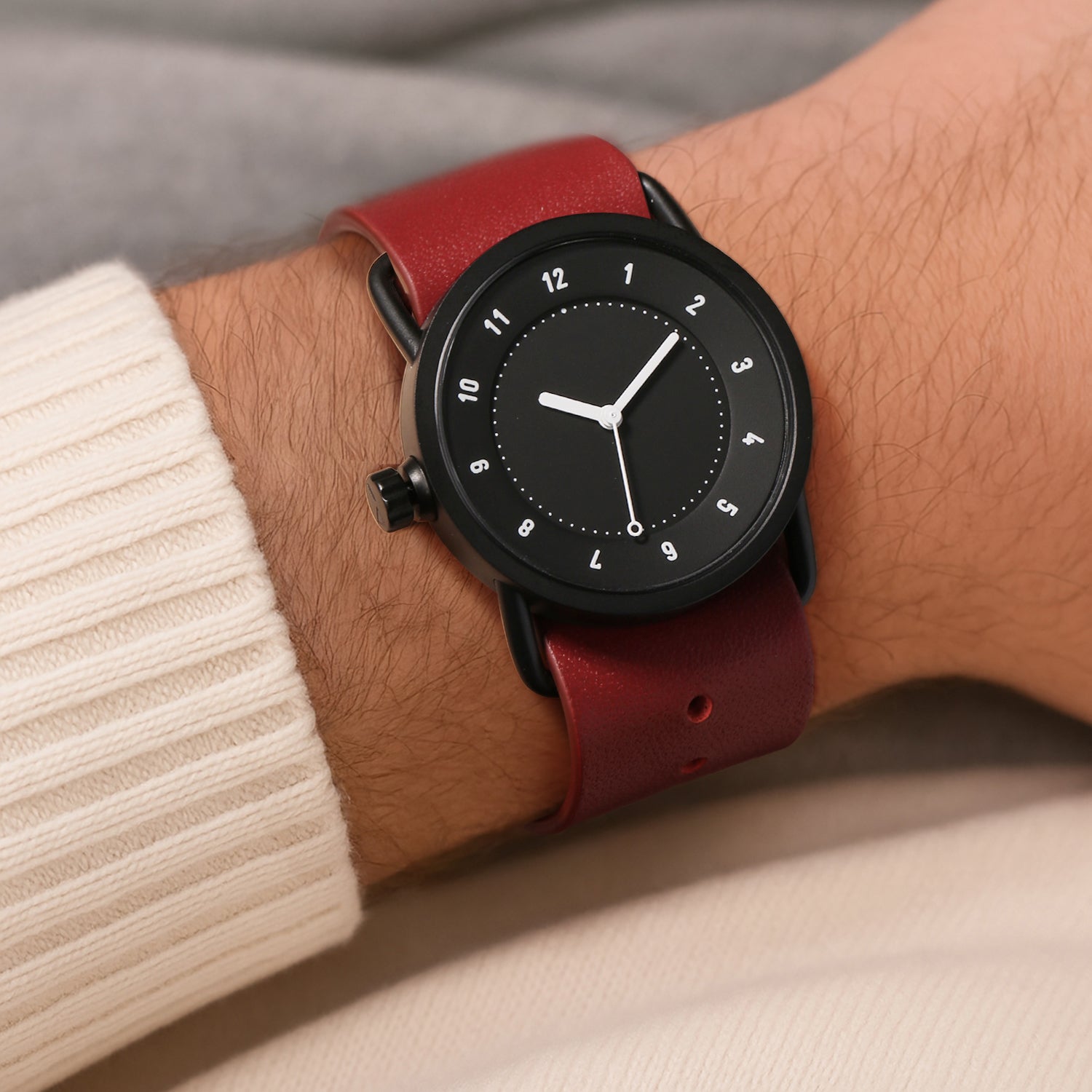 TID No.1 black dial watch worn with cream sweater and red background