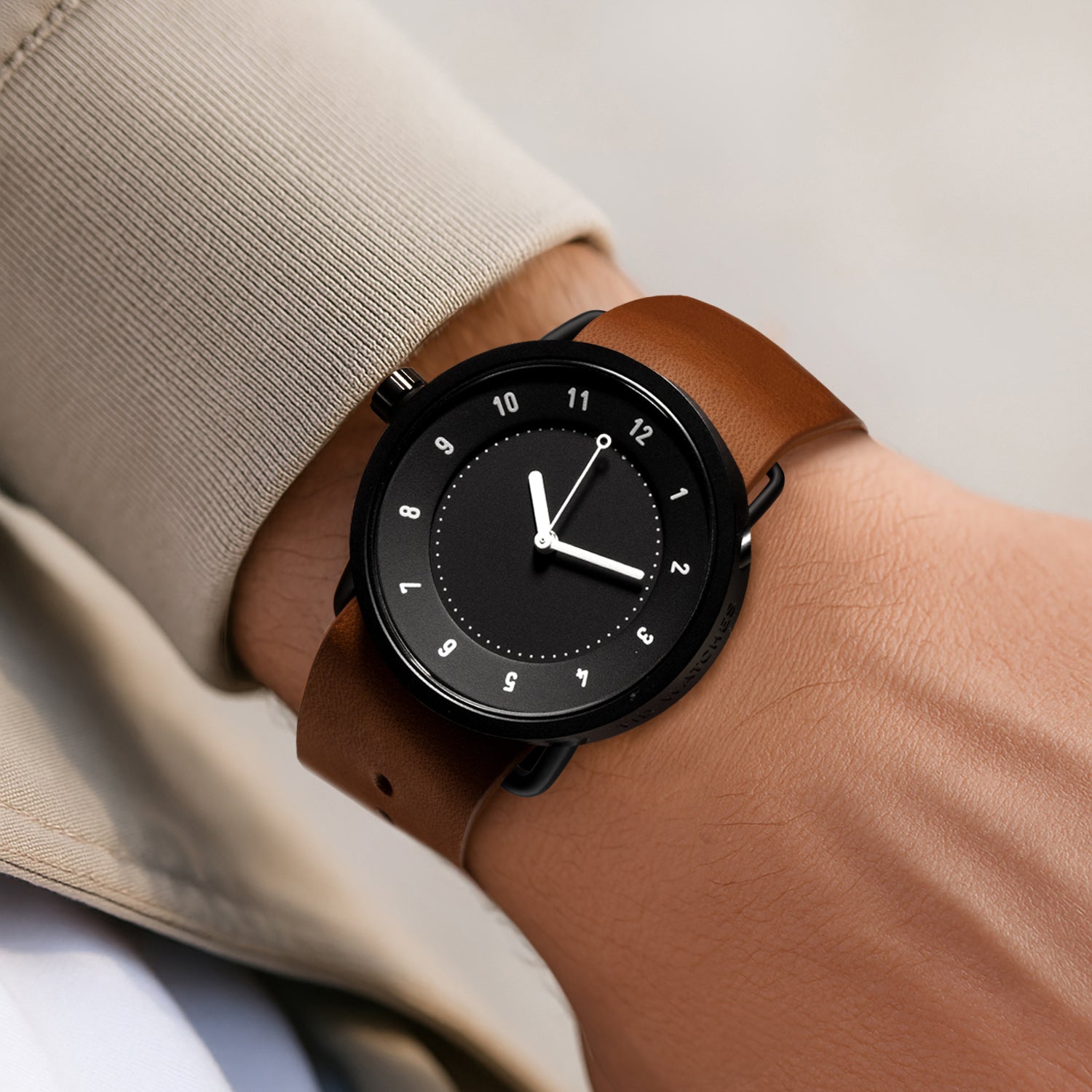 TID No.1 black leather strap watch worn with beige coat