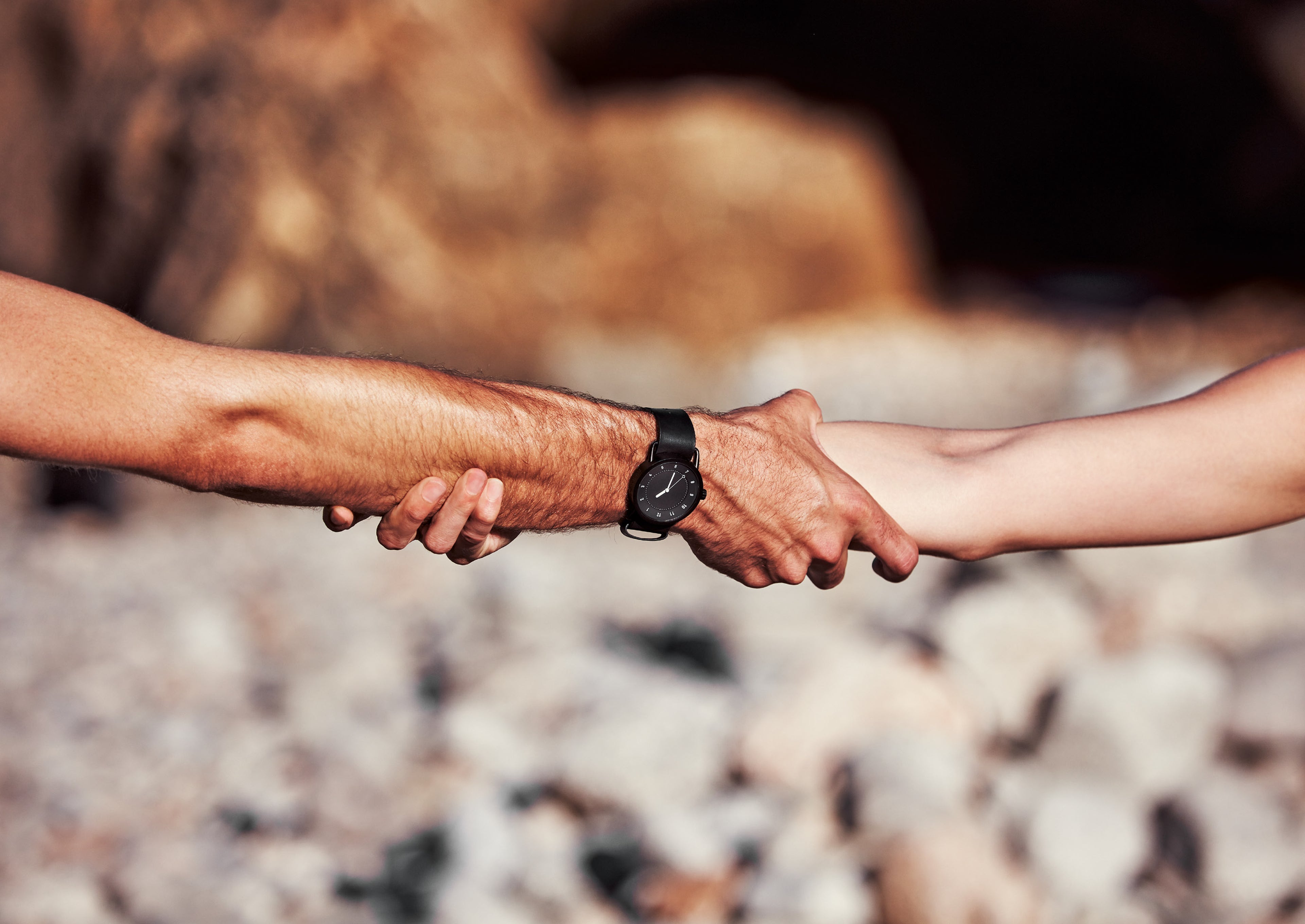TID black dial minimalist watch worn on wrist while holding hands outdoors