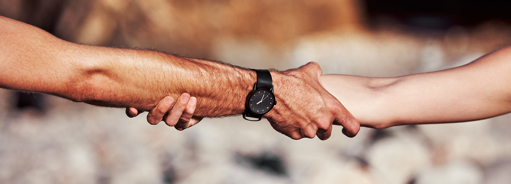 TID black dial minimalist watch worn on wrist while holding hands outdoors